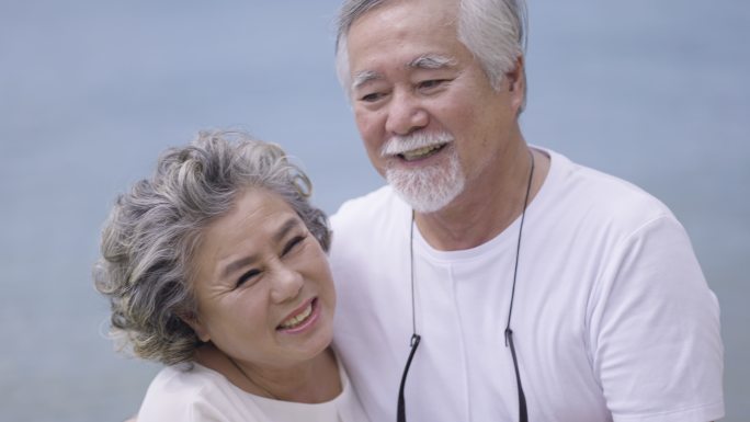 快乐的老年夫妇在海滩摆姿势