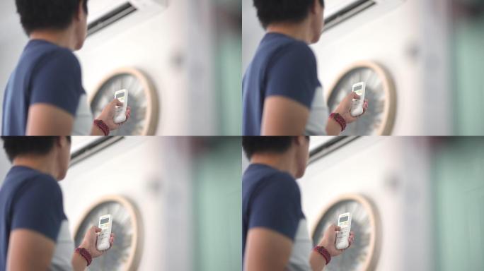 亚裔男子在家里用遥控器调节空调温度