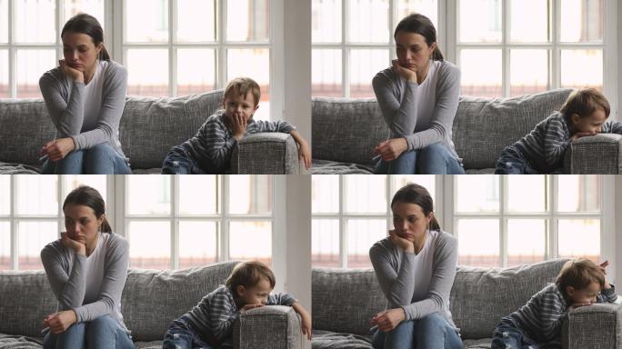 年轻女子和悲伤的学龄前小男孩坐在沙发上