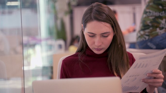 女孩正在检查桌上文件中的统计数据和报告。