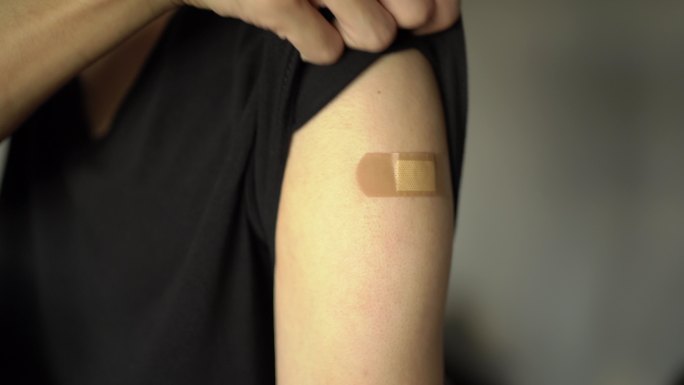 一名男子展示了注射疫苗时使用的粘性绷带。