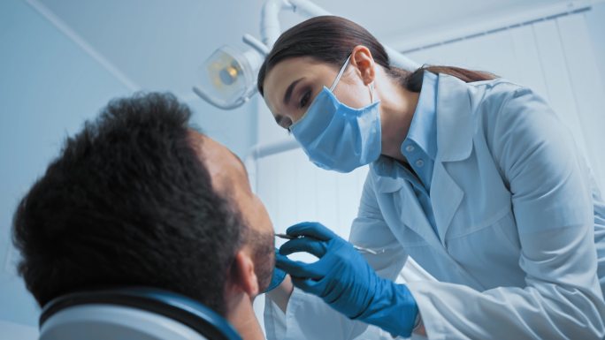 牙医使用牙科器械治疗患者