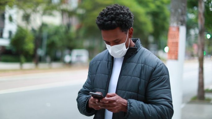男子戴着口罩在街头使用手机