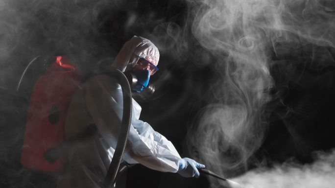 一名身穿防护服的男子喷洒消毒剂。