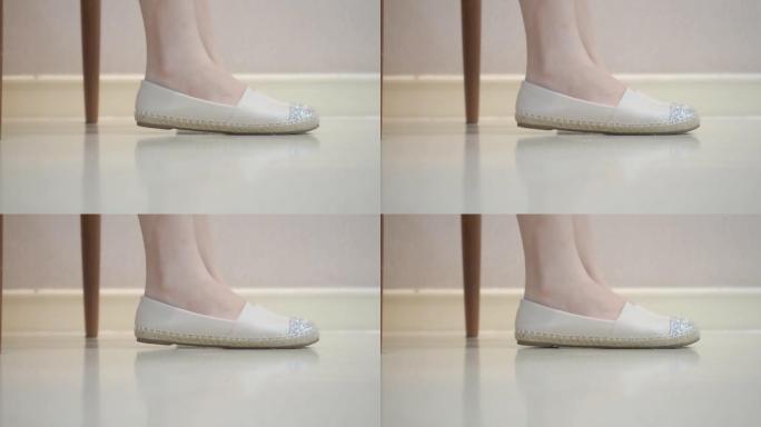 女性双脚在白色地板上颤抖。踢脚的概念。