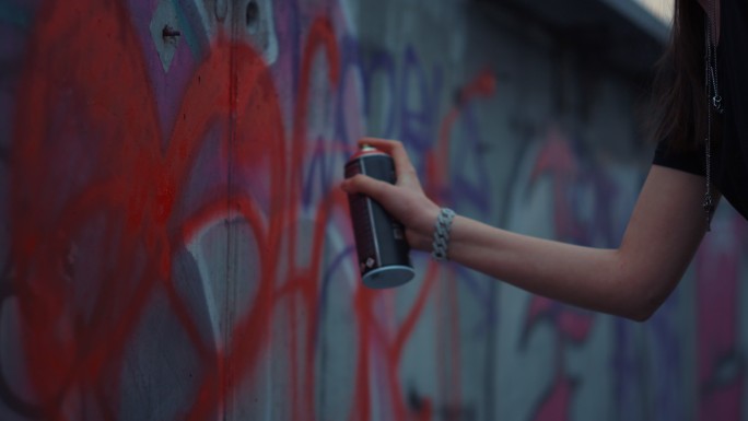 女人在街上的墙上手绘涂鸦。