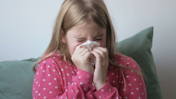 生病的女孩用餐巾纸擤鼻涕