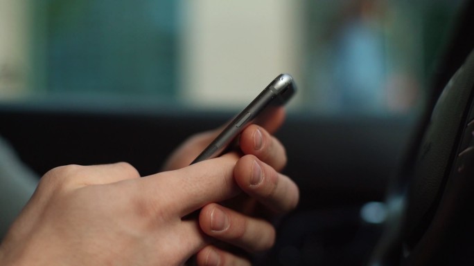 坐在车前用手机的男子