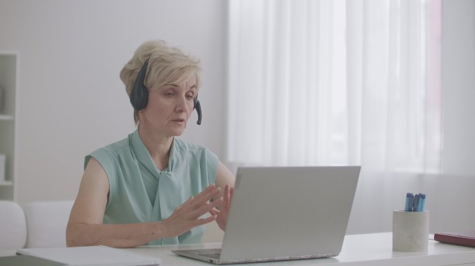 戴着耳机的女士正在用笔记本电脑接听电话