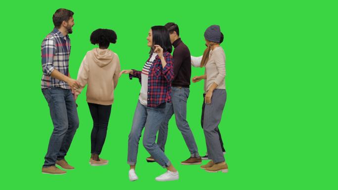一群快乐的年轻人在绿色屏幕上跳舞