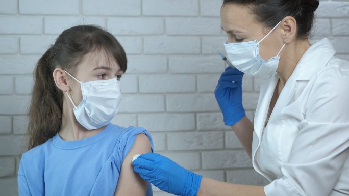 一名护士在办公室给一名儿童接种疫苗。