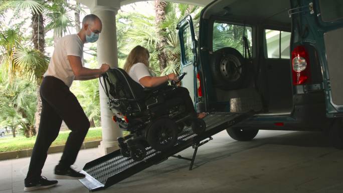 协助轮椅上的残疾妇女使用无障碍车辆