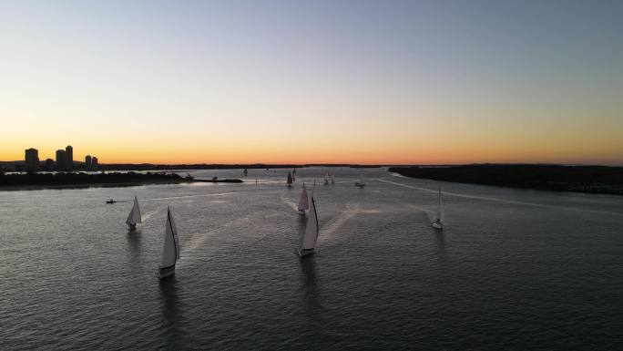 在下午的夕阳下，一群帆船在水面上竞速