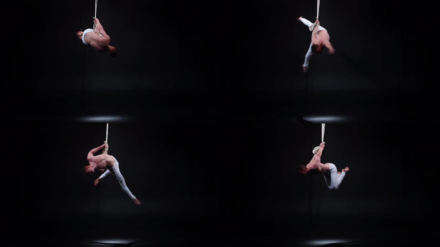 马戏团空中艺术家在黑色工作室的吊带上表演