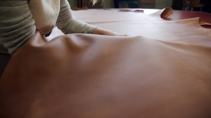 一个工匠在桌子上打磨一大块皮革