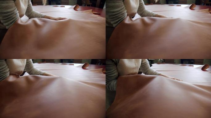 一个工匠在桌子上打磨一大块皮革