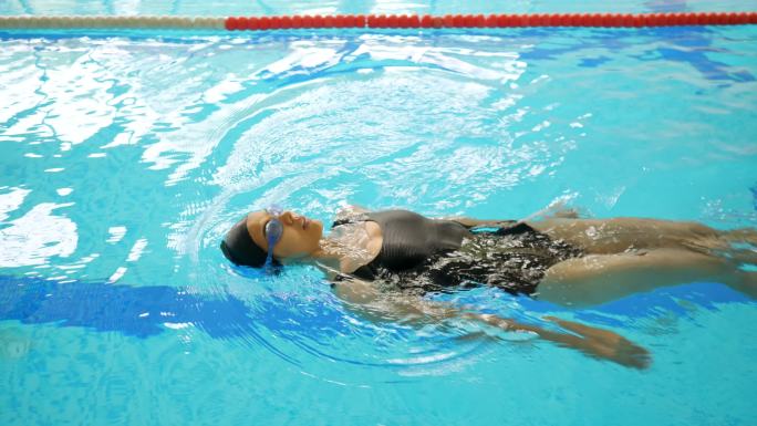 穿黑衣服的女运动员在泳池里仰泳