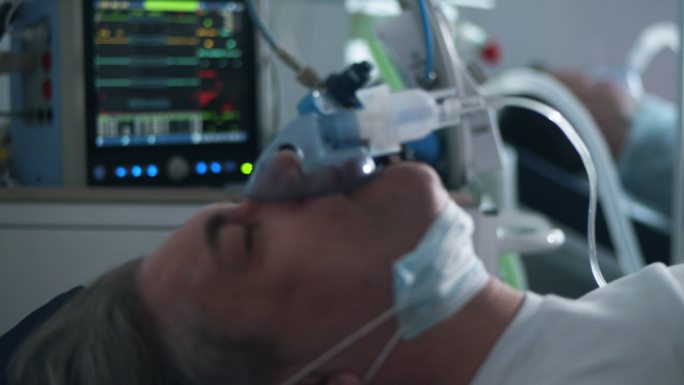一名带呼吸机的男子躺在临床病房。