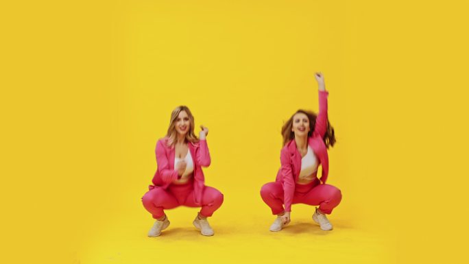 两个女孩在黄色背景下跳舞
