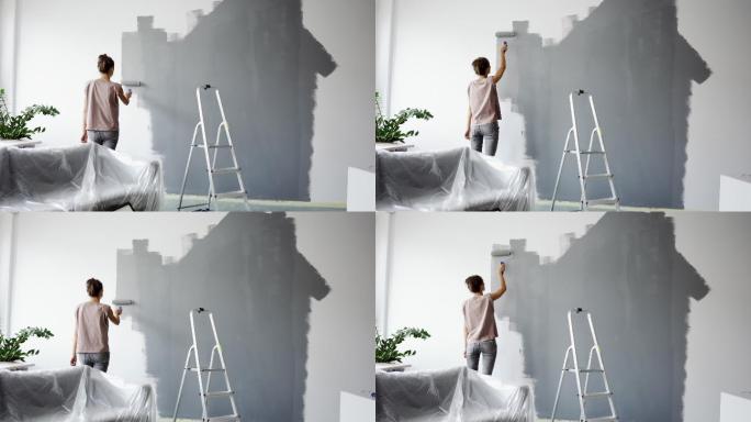 年轻女子用滚筒粉刷墙壁