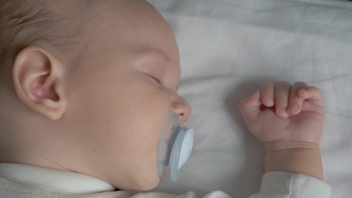一个正在睡觉的婴儿吮吸奶嘴的特写镜头