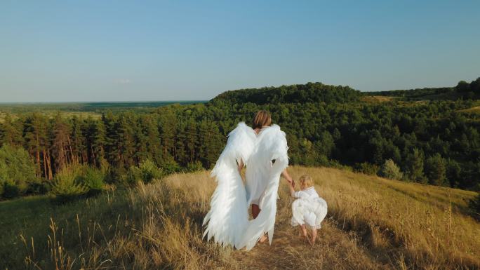 一个女孩带着孩子打扮成天使行走在草地上