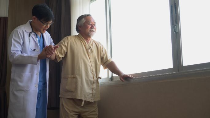 年轻的亚洲医生在医院帮助老人走路