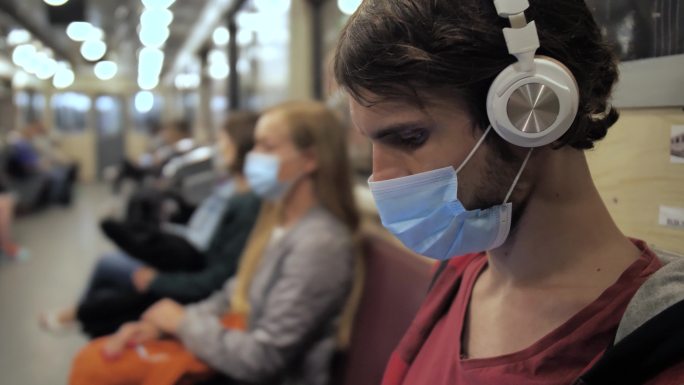 地铁列车上的戴口罩和耳机的人