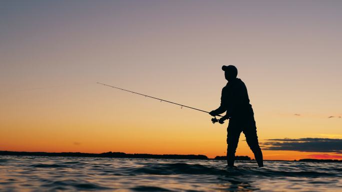 一名男子抛下鱼竿海钓钓鱼人大海夕阳下钓鱼