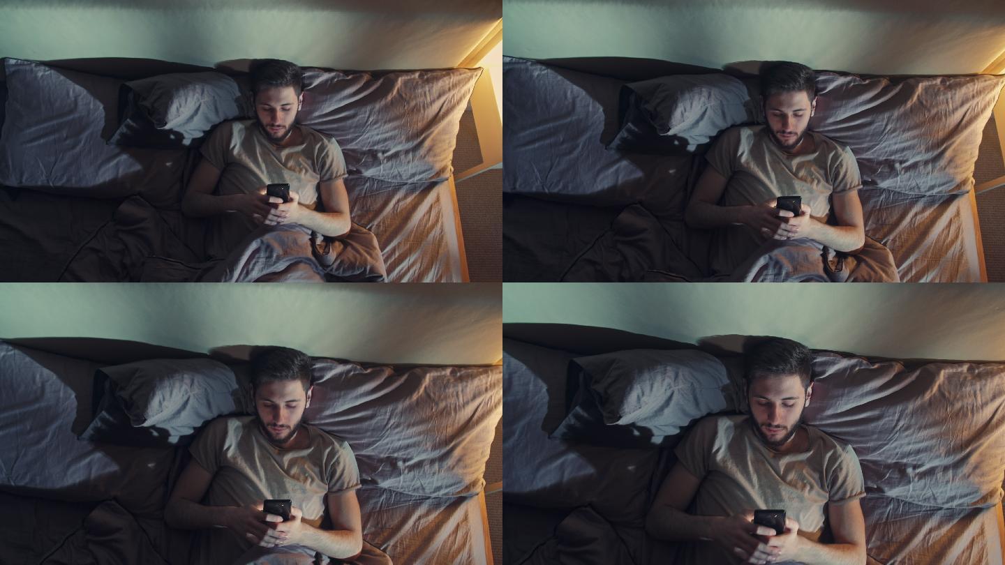 无聊的男人睡觉前使用智能手机。