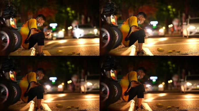 夜幕下坐在马路边的快递小哥