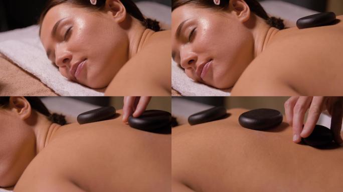 美丽女子在水疗中心做热石按摩