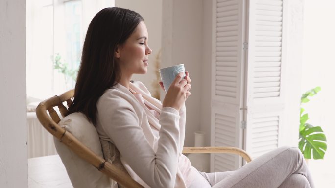 安静的女人喝着热茶，在家呼吸新鲜空气
