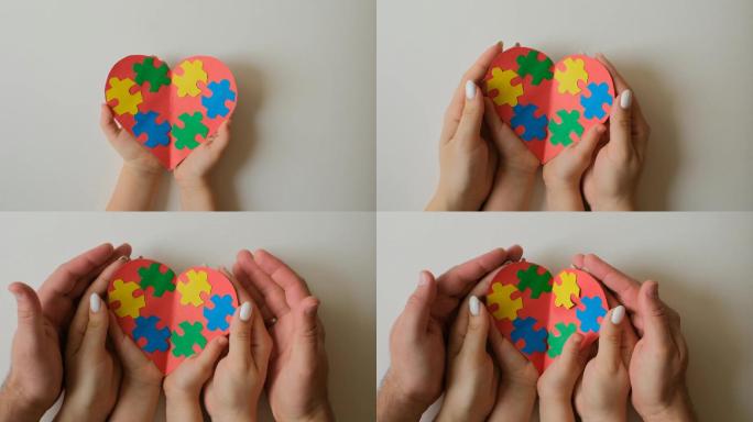 大人和小孩手里拿着一颗装饰着彩色拼图的心