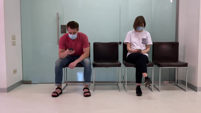 年轻人戴着口罩，在医院排队等待医生的预约