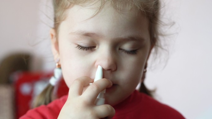 小女孩在鼻子里喷了一种喷雾，家庭治疗。