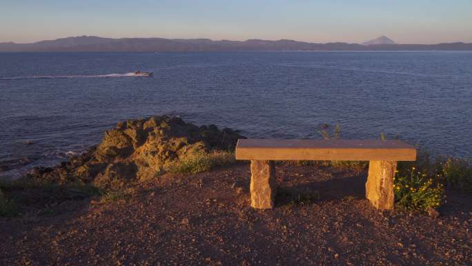 希腊日落时悬崖边上的石凳