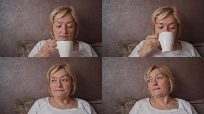老妇人情绪低落，躺在床上喝茶。