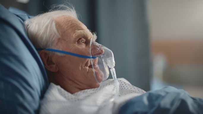 医院病房：老人戴着氧气面罩躺在床上休息