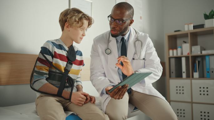 家庭医生与一名戴着护臂的小男孩交谈