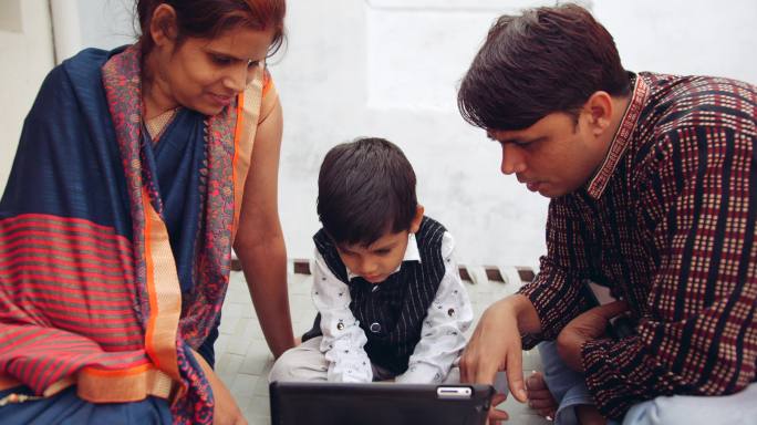 年幼的儿子和父母一起使用科技设备