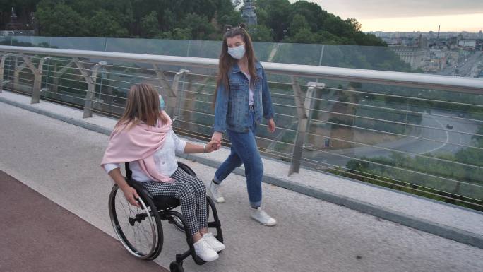 残疾母亲和戴着戴口罩的女孩走在户外