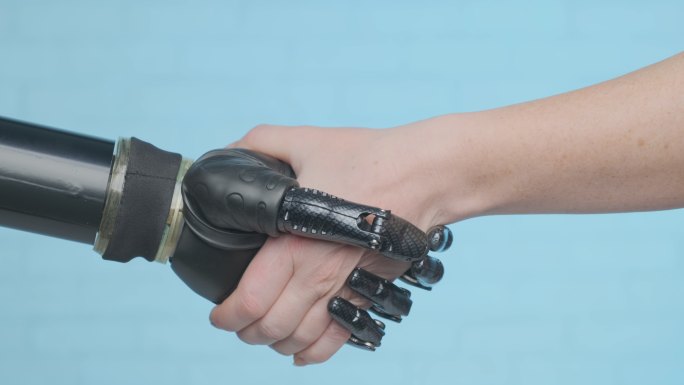 在蓝色背景中拟人机器人手臂和人手握手。