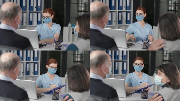 戴着医用口罩的女医生在医院办公室接待病人