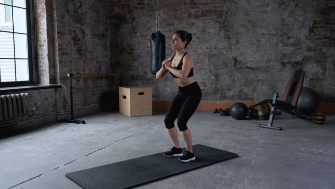 女运动员正在健身房做蹲式运动