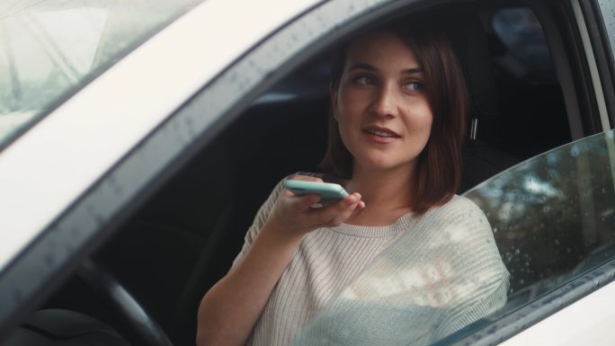 女人坐在车内使用智能手机语音识别功能