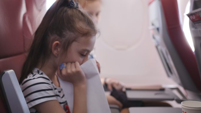 飞机上的小女孩吐在纸袋里。