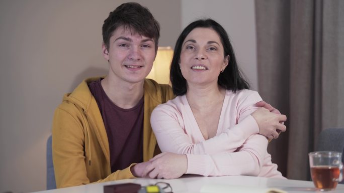 儿子和母亲坐在室内的桌子旁