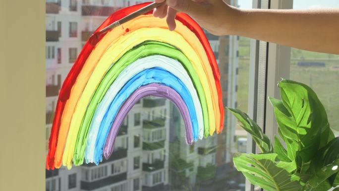 在家隔离期间，女孩在窗户上画彩虹。