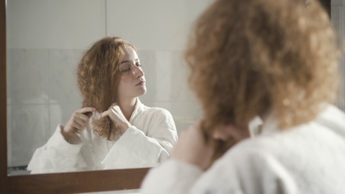 穿着白色浴袍的女士在浴室镜子里